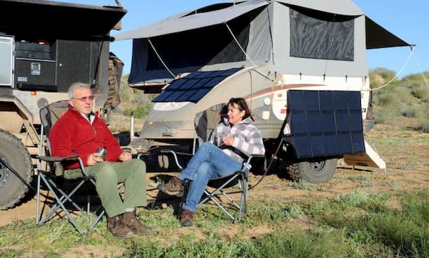 man and a woman camping with their vehicle and foldable solar panels