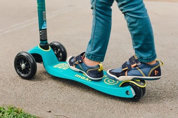 boy standing on scooter