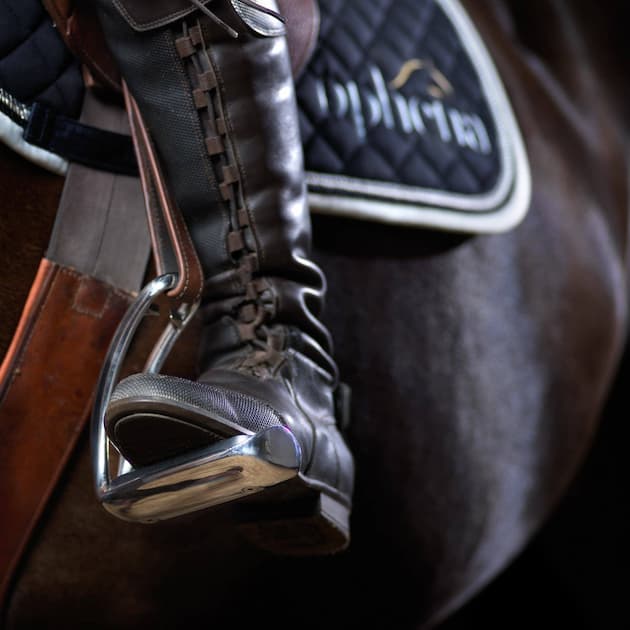 To prevent the risk of getting stuck in the stirrup with your foot, you should wear boots with a high heel and covered ankle. Safety strips can be a good option as well as they open up, so if you should fall off, your foot can come free.