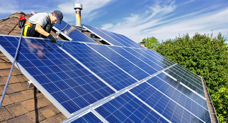 Man installing alternative energy photovoltaic solar panels on roof