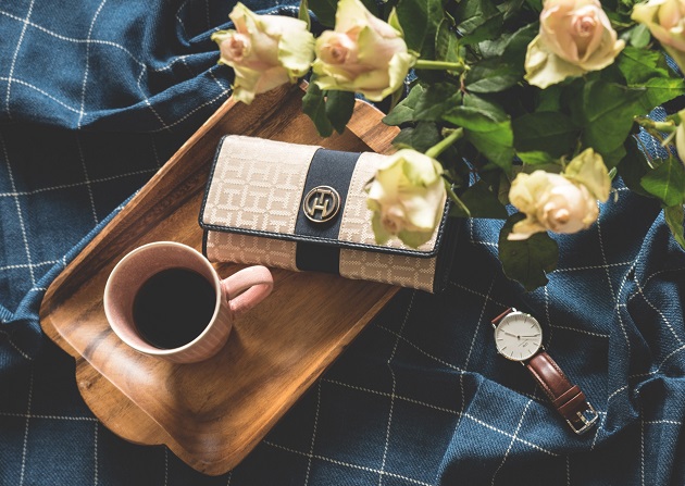 women wallet next to a cup of coffee on wooden trey 